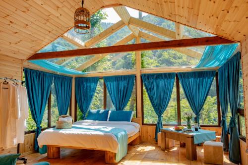ein Schlafzimmer mit einem Bett in einem Zimmer mit blauen Vorhängen in der Unterkunft SkyDoor_ცისკარი in Batumi