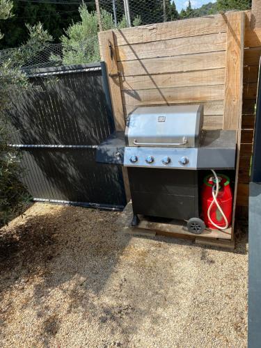 un gril posé dans une cour arrière à côté d'une clôture dans l'établissement Maison aux pieds des Alpilles, à Noves