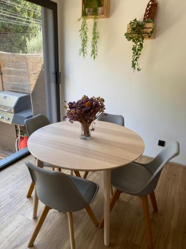 une table avec des chaises et un vase de fleurs dessus dans l'établissement Maison aux pieds des Alpilles, à Noves