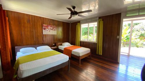 een slaapkamer met 2 bedden en een plafondventilator bij La Baula Lodge in Tortuguero
