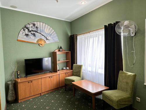 ein Wohnzimmer mit einem TV, 2 Stühlen und einem Tisch in der Unterkunft RANDEVU in Schytomyr