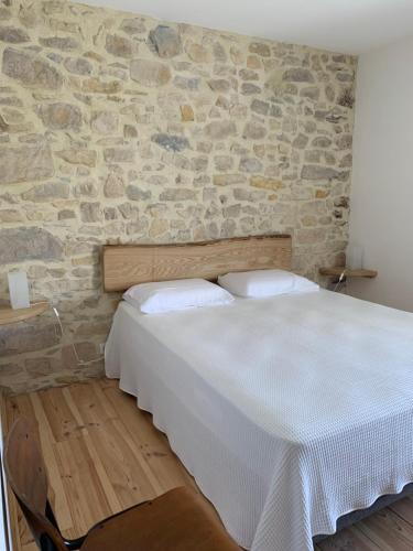 Bett in einem Zimmer mit einer Steinmauer in der Unterkunft LA BERGERIE in Domessargues