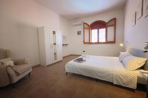 a bedroom with a bed and a chair and a window at Casa di Sara&Anna in Avola