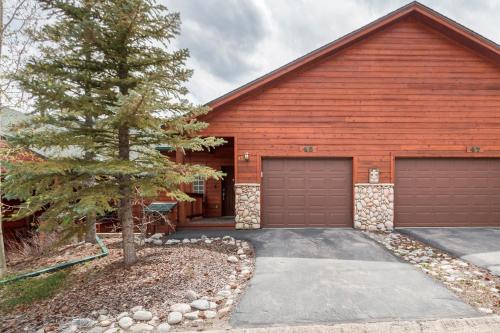 a red house with two garage doors and a tree at Lookout Ridge 45 by Great Western Lodging in Dillon