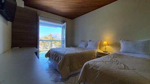 1 Schlafzimmer mit 2 Betten und einem Fenster mit Aussicht in der Unterkunft Pousada In Garden in Teresópolis