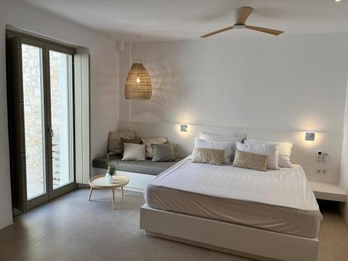 a white bedroom with a bed and a couch at Olive Breeze Villa , Naousa in Kampos Paros