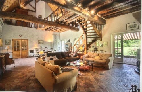 un grand salon avec des canapés et une table dans l'établissement Gîte de charme - La Boursicauderie, à Le Grand Chaloy