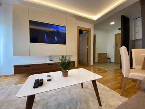 a living room with a white table and a tv at Zlatibor Argonath Relax&Spa in Zlatibor