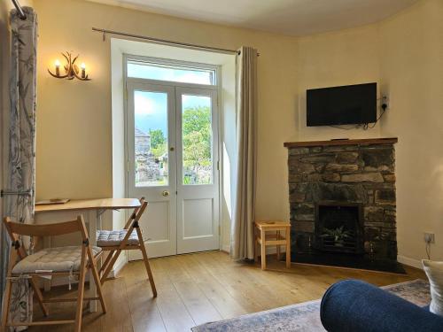 a living room with a table and a fireplace at Cosy peaceful one-bedroom cottage in Pitlochry in Pitlochry
