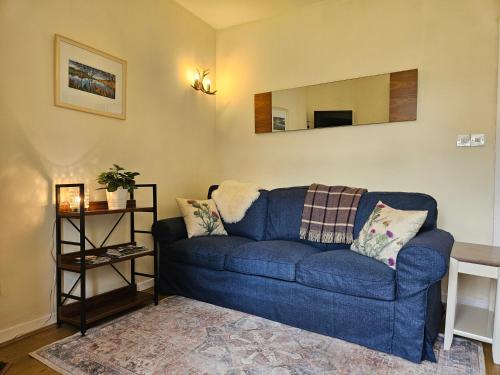 a blue couch in a living room with a mirror at Cosy peaceful one-bedroom cottage in Pitlochry in Pitlochry