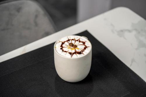 a white cup with a flower on top of a table at Swiss Spirit Second Dammam Industrial City in Dammam