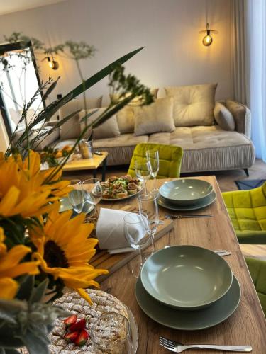 a living room with a table with plates and wine glasses at Olivina Park Spa - domki z dostępem do krytego basenu, saun, wyżywienia i atrakcji dla dzieci in Niechorze