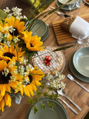 a wooden table with yellow flowers and plates on it at Olivina Park Spa - domki z dostępem do krytego basenu, saun, wyżywienia i atrakcji dla dzieci in Niechorze