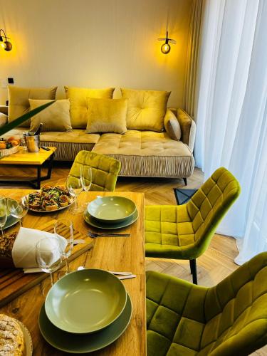 a living room with a couch and a table with green chairs at Olivina Park Spa - domki z dostępem do krytego basenu, saun, wyżywienia i atrakcji dla dzieci in Niechorze