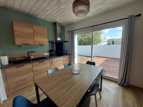 une cuisine avec une table en bois et une terrasse en bois dans l'établissement Maison de vacances - Classé meublé de tourisme 3 étoiles, à L'Ile d'Yeu