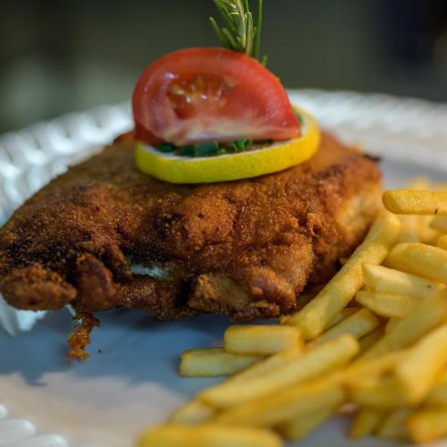 a piece of chicken with a tomato and french fries at Gasthof Löwen, Heitersheim in Heitersheim
