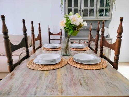 een houten tafel met borden en een vaas met bloemen bij Apartamento en el barrio marítimo del Serrallo in Tarragona