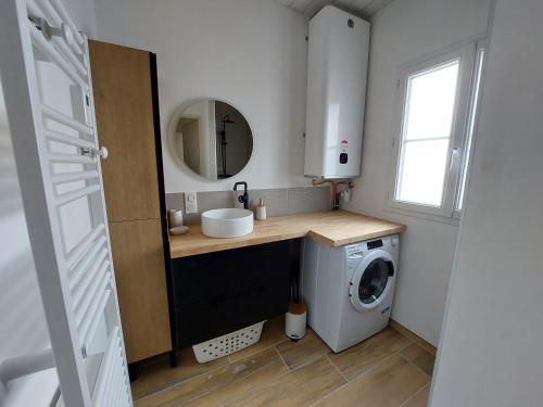 a bathroom with a sink and a washing machine at Maison de vacances - Classé meublé de tourisme 3 étoiles in L'Ile d'Yeu