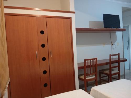 a bedroom with a wooden cabinet and a table at Mariachis Hotel in Passos