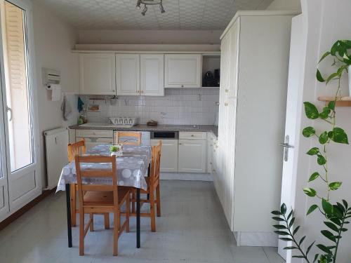 une cuisine avec une table, des chaises et des armoires blanches dans l'établissement Médipôle T2 avec un garage gratuit sur place, 16min à centre ville Lyon en métro A, à Villeurbanne
