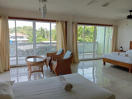a bedroom with a bed and chairs and a balcony at Los Balcones Over The Sea in Carenero