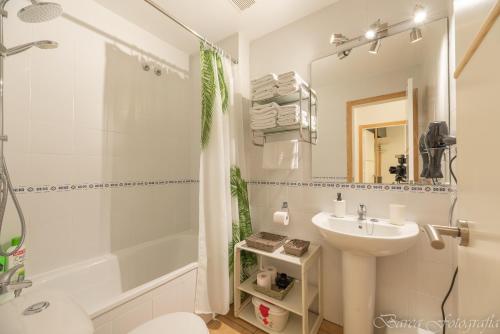 y baño blanco con lavabo y ducha. en Apartamento Playa La Barrosa, en Chiclana de la Frontera