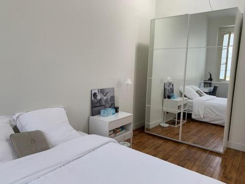 une chambre avec un lit blanc et un miroir dans l'établissement Appartement Tour Eiffel Invalides, à Paris