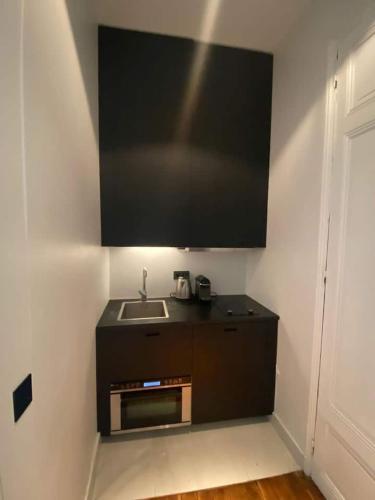 Il comprend une cuisine avec un évier et une télévision murale. dans l'établissement Appartement Tour Eiffel Invalides, à Paris