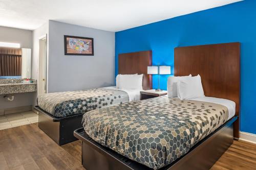 two beds in a hotel room with blue walls at Econo Lodge Inn & Suites Virginia Beach - Norfolk in Virginia Beach