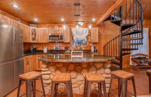 a kitchen with a large island with stools and a staircase at The Buckhorn by Stony Brook Cabins in Gatlinburg