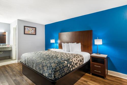 a hotel room with a bed and a blue wall at Econo Lodge Inn & Suites Virginia Beach - Norfolk in Virginia Beach