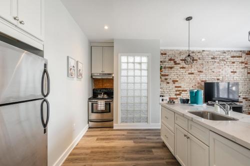 a kitchen with white cabinets and a brick wall at Cozy Condo on James Street North in Hamilton