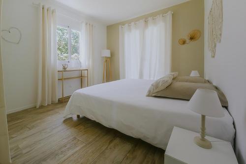 a white bedroom with a large bed and a window at LA VILLA ALBA in Les Issambres