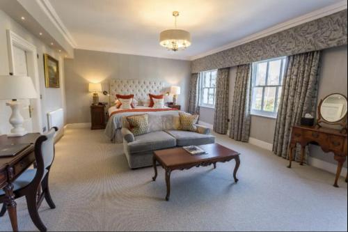 a bedroom with a bed and a couch and a table at Storrs Hall Hotel on the shore of Lake Windermere in Bowness-on-Windermere