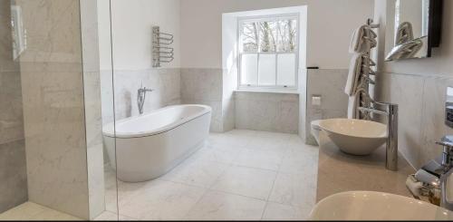 a white bathroom with a tub and a sink at Storrs Hall Hotel on the shore of Lake Windermere in Bowness-on-Windermere
