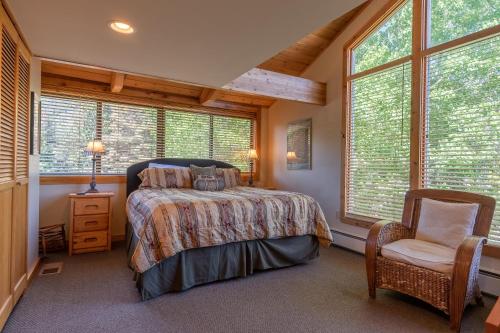 a bedroom with a bed and a chair and windows at Alpine Villa Condo 1 in Ketchum