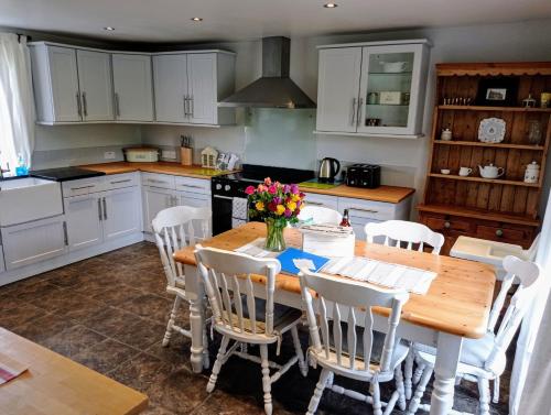 una cucina con tavolo in legno e armadietti bianchi di Whitehill Cottage a Castlewellan