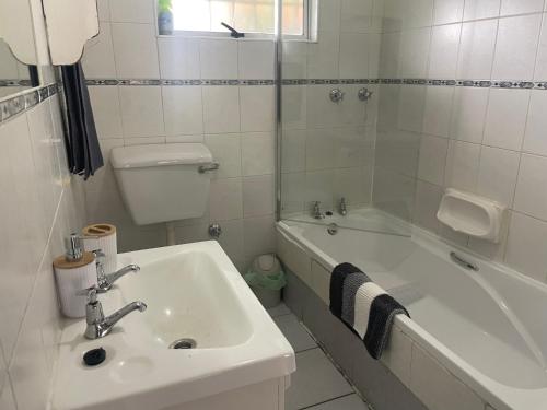 a bathroom with a sink and a tub and a toilet at Lente Beach Cottage, Fleur Park, Gordon's Bay in Gordonʼs Bay