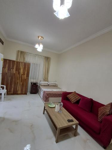 a living room with a red couch and a bed at Aalia building studio furnished flat in Al Ḩamīdīyah