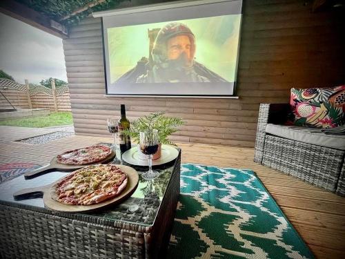 a table with two pizzas and a movie projected on a wall at Between Rivers Camping @ The Old George Inn in Sykehouse