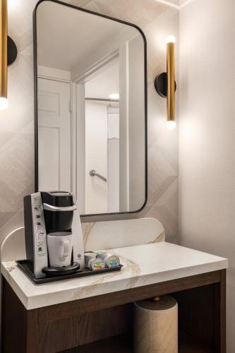 a bathroom with a mirror and a coffee maker on a counter at Crowne Plaza Louisville Airport Expo Ctr by IHG in Louisville