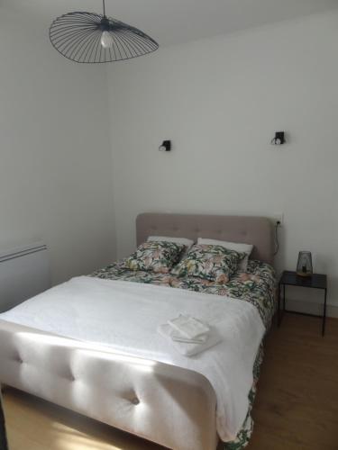 une chambre avec un lit avec des draps blancs et une lampe dans l'établissement ''La Clé des Sources'' - Bel appartement 2 pièces - En bord d'Allier et près des thermes, à Vichy