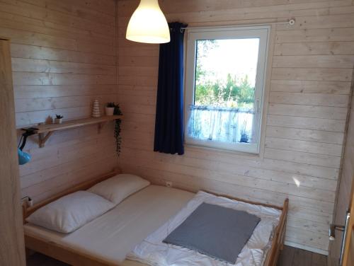 ein kleines Bett in einem Zimmer mit Fenster in der Unterkunft Domki na Leśnej in Ustronie Morskie