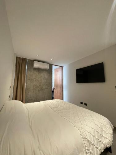 a bedroom with a white bed and a flat screen tv at Casa Valentina Habitación 3 in Aguascalientes