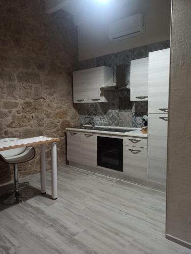 a kitchen with white cabinets and a table in it at Piazza San Giorgio in Dolianova