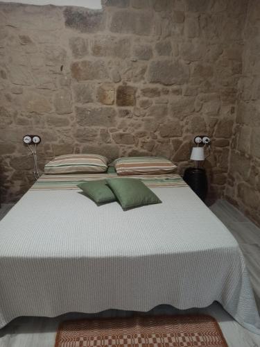 a bed in a room with a stone wall at Piazza San Giorgio in Dolianova