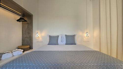 a bedroom with a large bed with blue pillows at Manesis Suites in Pollonia
