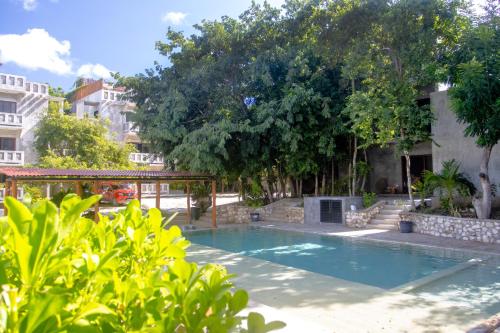 a swimming pool in a yard with trees and a building at Hotel Casa Tortuga Tulum - Cenotes Park Inclusive in Tulum