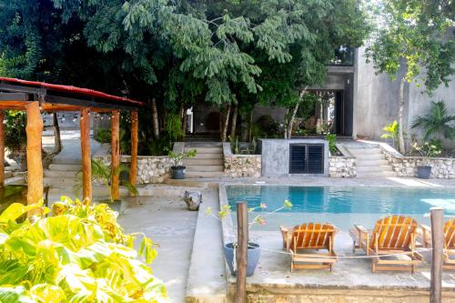 a swimming pool with two chairs and a table at Hotel Casa Tortuga Tulum - Cenotes Park Inclusive in Tulum