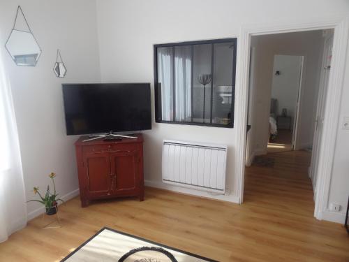 un salon avec une télévision à écran plat sur un mur dans l'établissement ''La Clé des Sources'' - Bel appartement 2 pièces - En bord d'Allier et près des thermes, à Vichy